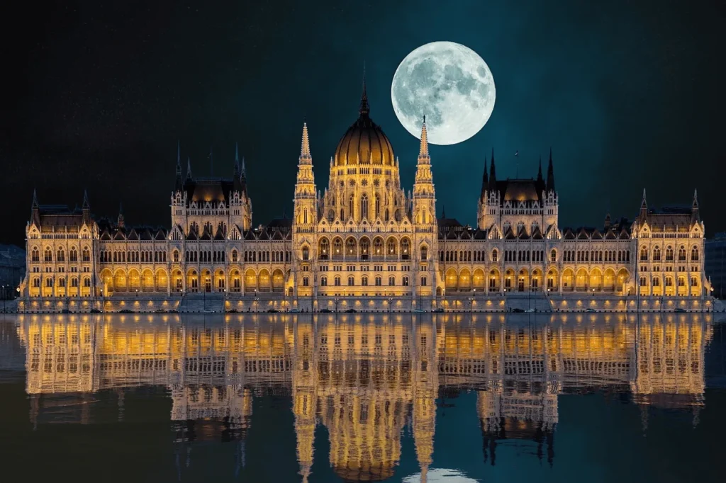 Le Parlement de Budapest de nuit sous la pleine lune, reflété dans le Danube